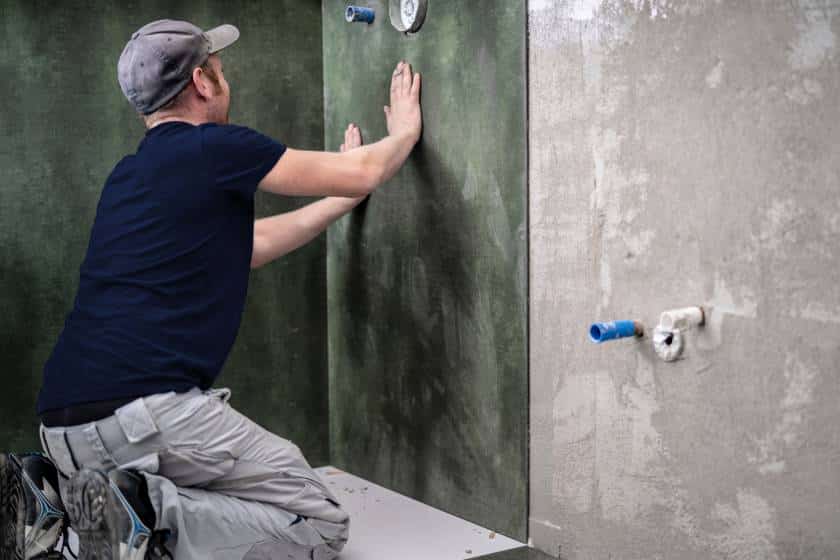 Employé Doucéo posant des panneaux muraux dans une douche à l'italienne