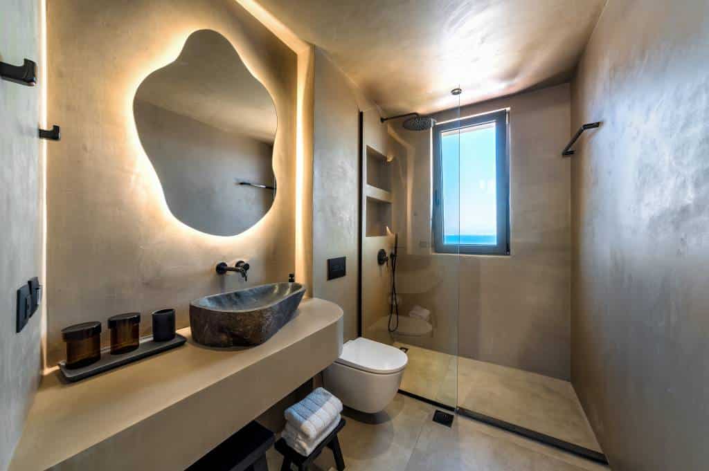 Photo de l'intérieur d'une salle de bain avec des éléments a forme organiques comme un lavabo, un miroir en tendance pour 2026